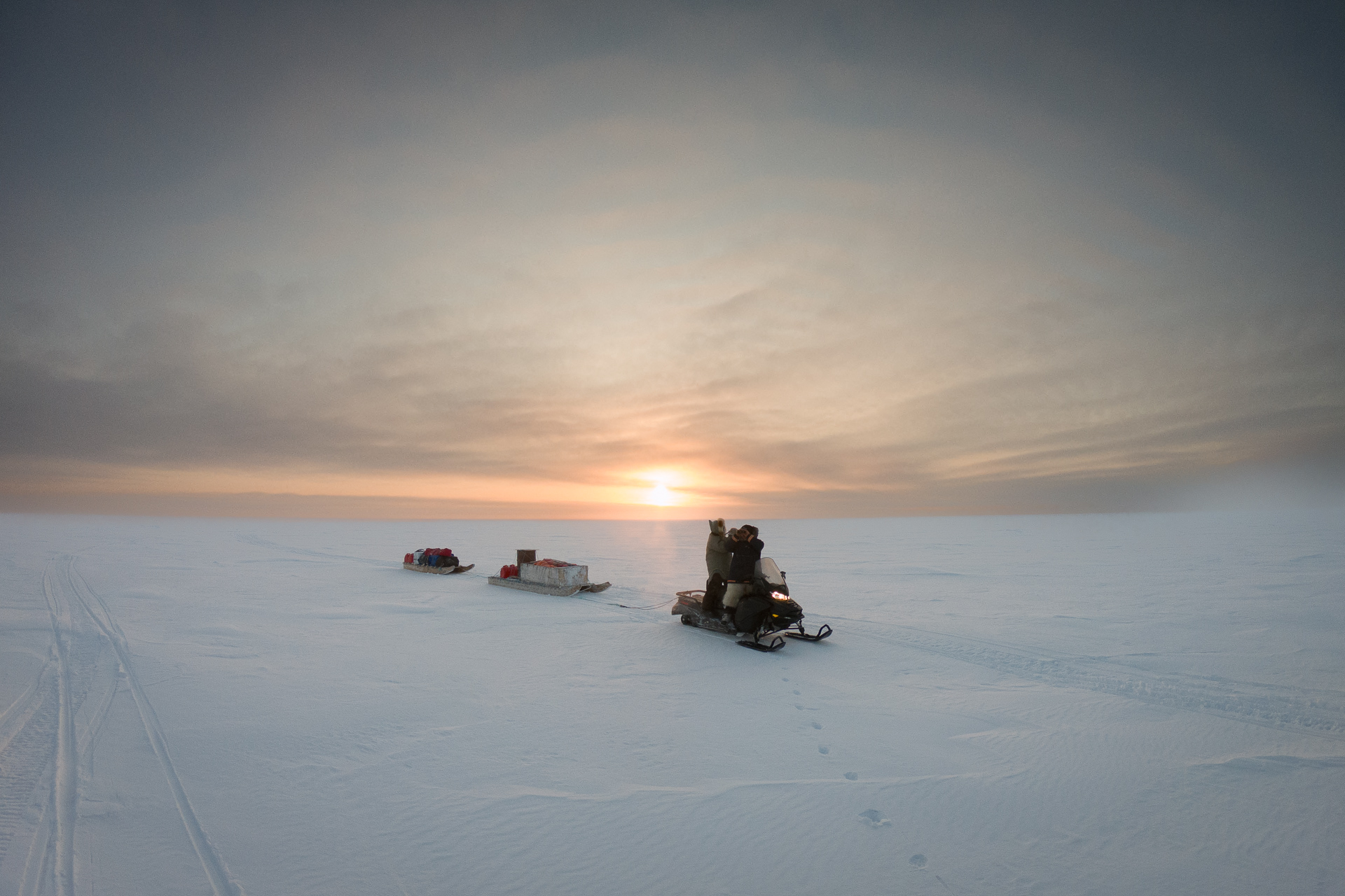 Arctic expedition crossing the infinite white horizon at sunset
